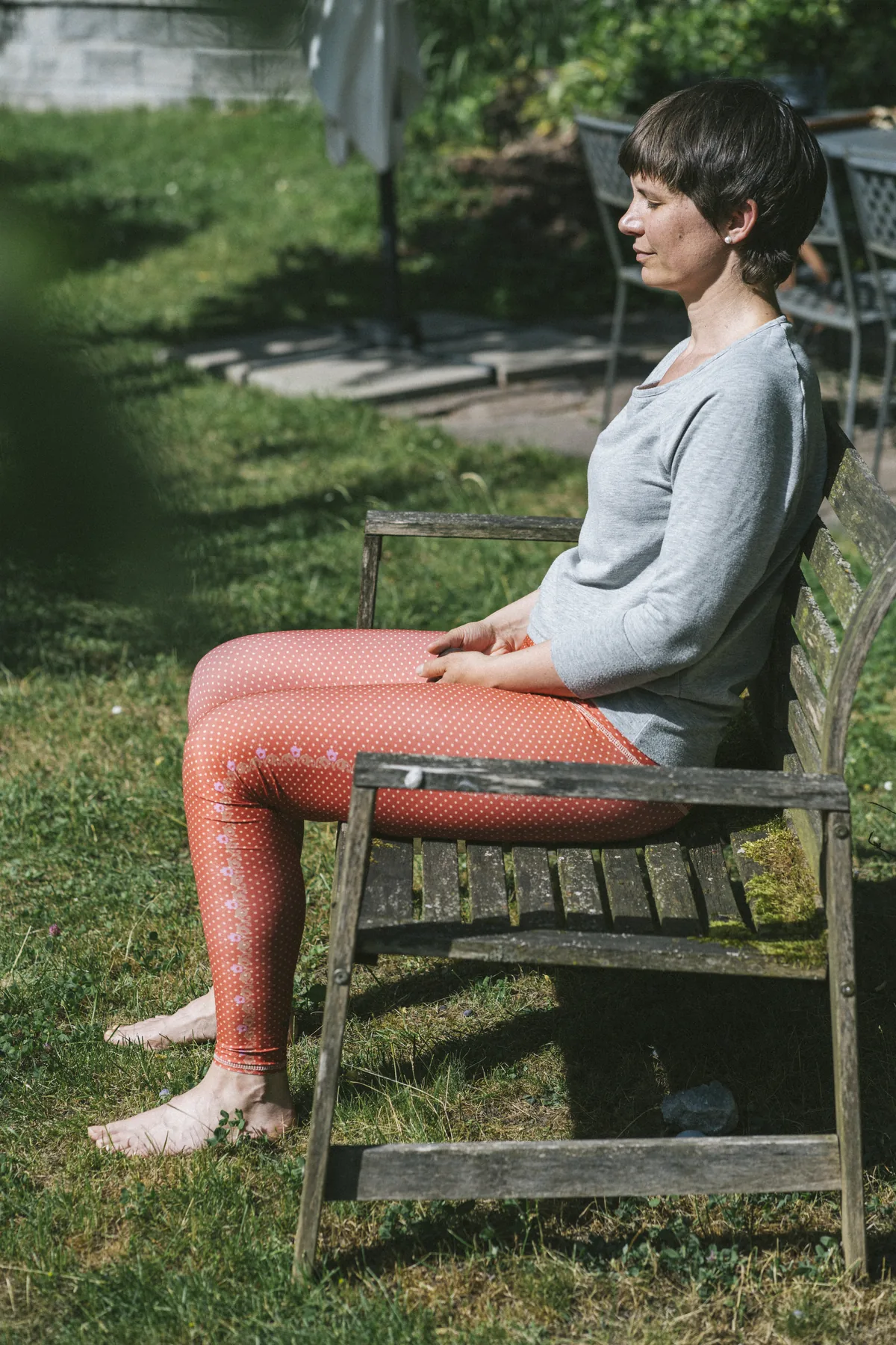 Julia Badum sitzt in Meditation auf einer Gartenbank