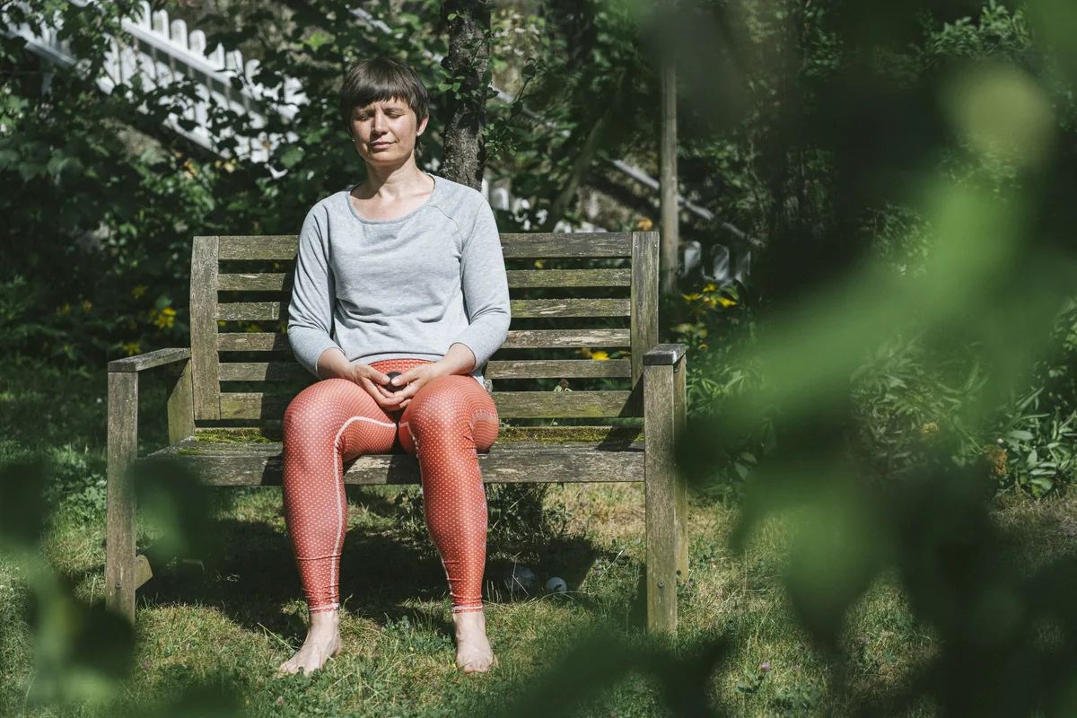 Julia Badum in Meditation auf einer Gartenbank